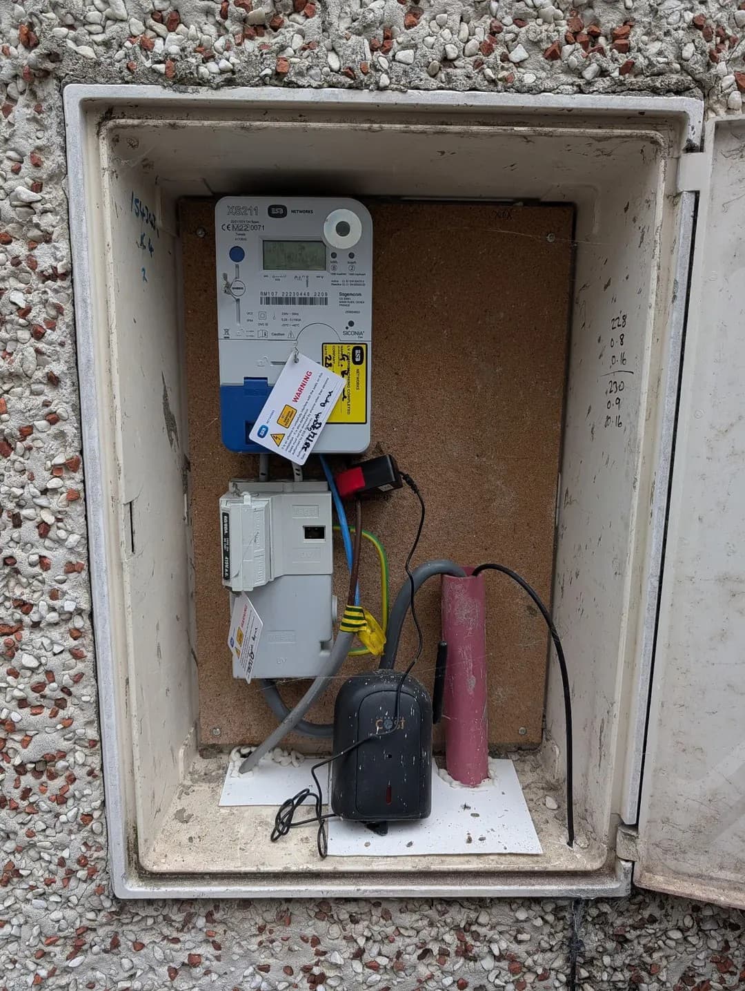 Open meter cabinet with smart meter, main fuse and tails visible